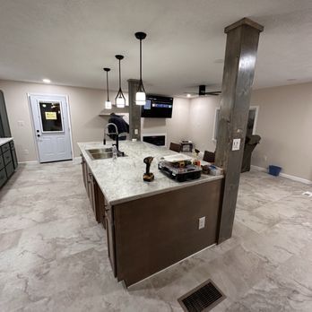 Kitchen with island, pendant lights, and appliances; brown cabinets, gray countertops, and tile flooring.