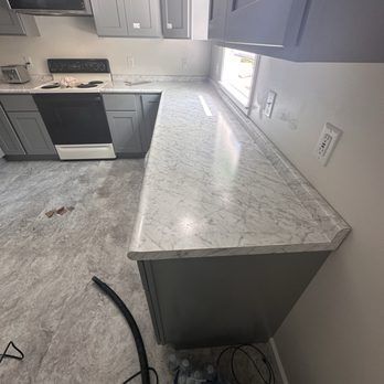 Kitchen with gray cabinets, a white countertop, and a window.