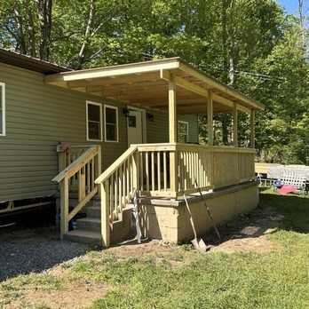 Newly constructed wooden porch with steps, attached to a light green house.