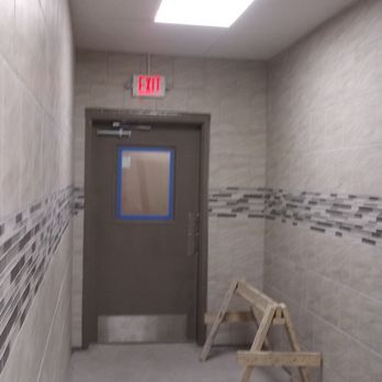 Interior hallway with a closed door, exit sign, and wooden sawhorse.