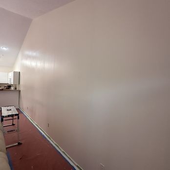 Interior wall painted light pink with visible brush strokes. Room has red floor and a countertop.