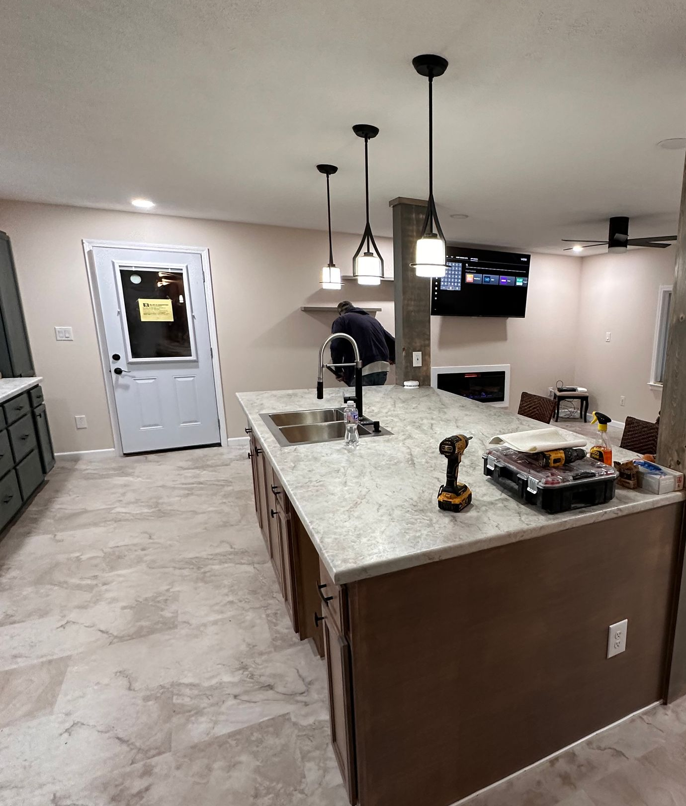 Modern kitchen with white cabinets, marble countertops, stainless steel appliances, and a wooden island with seating.