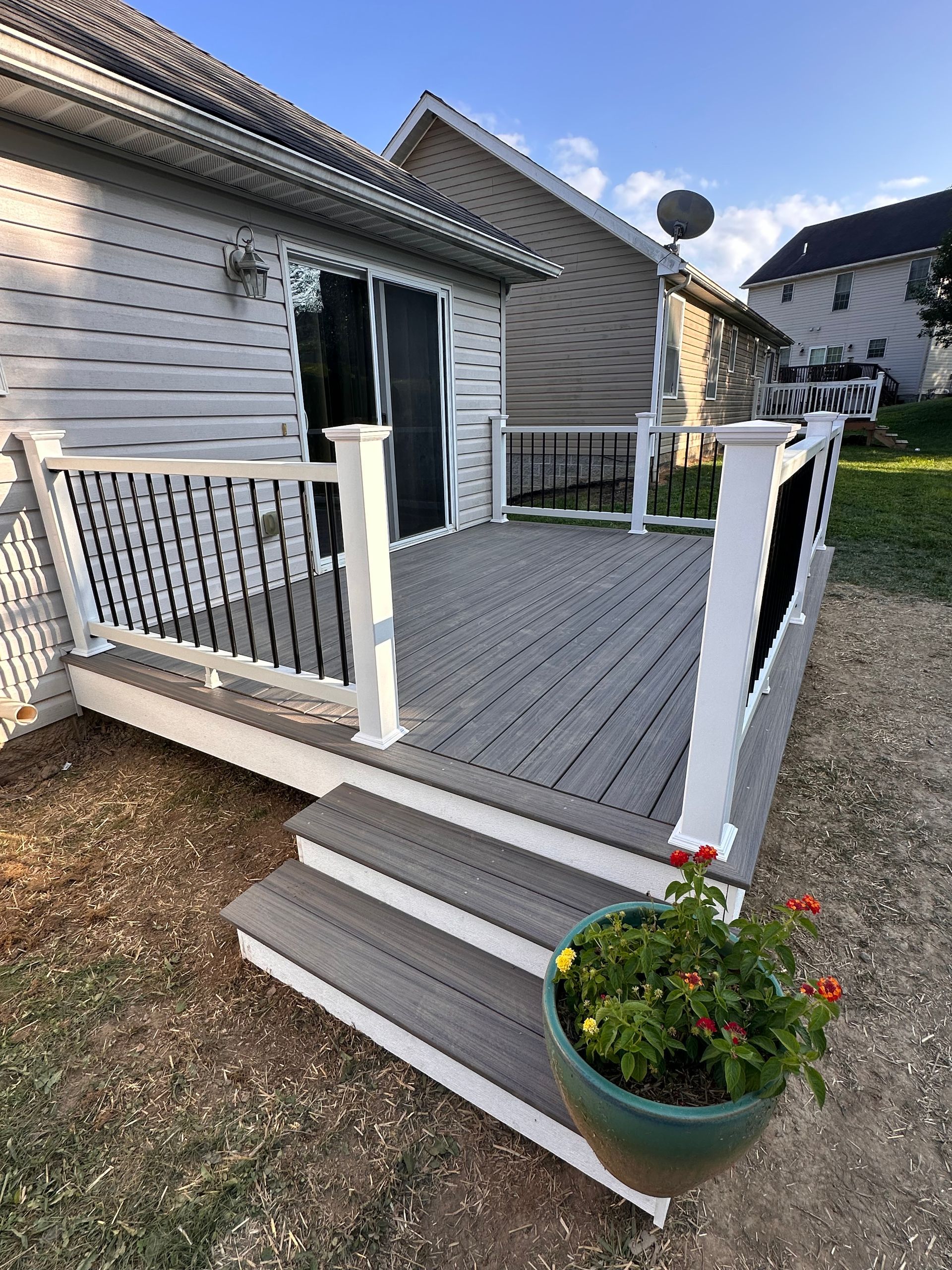 Man building a wooden deck in a backyard, using a drill.