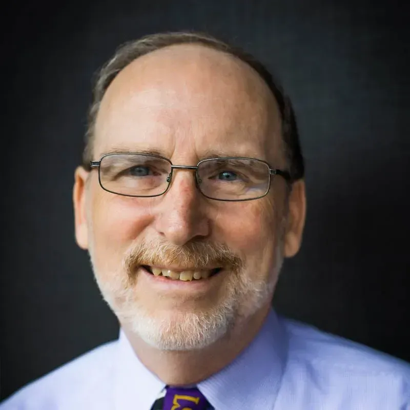 A man with glasses and a beard is smiling for the camera.