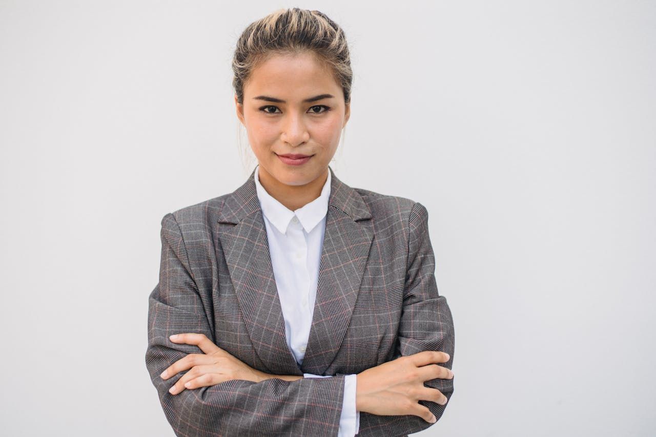 A confident businesswoman stands with arms crossed, exuding professionalism and determination in her