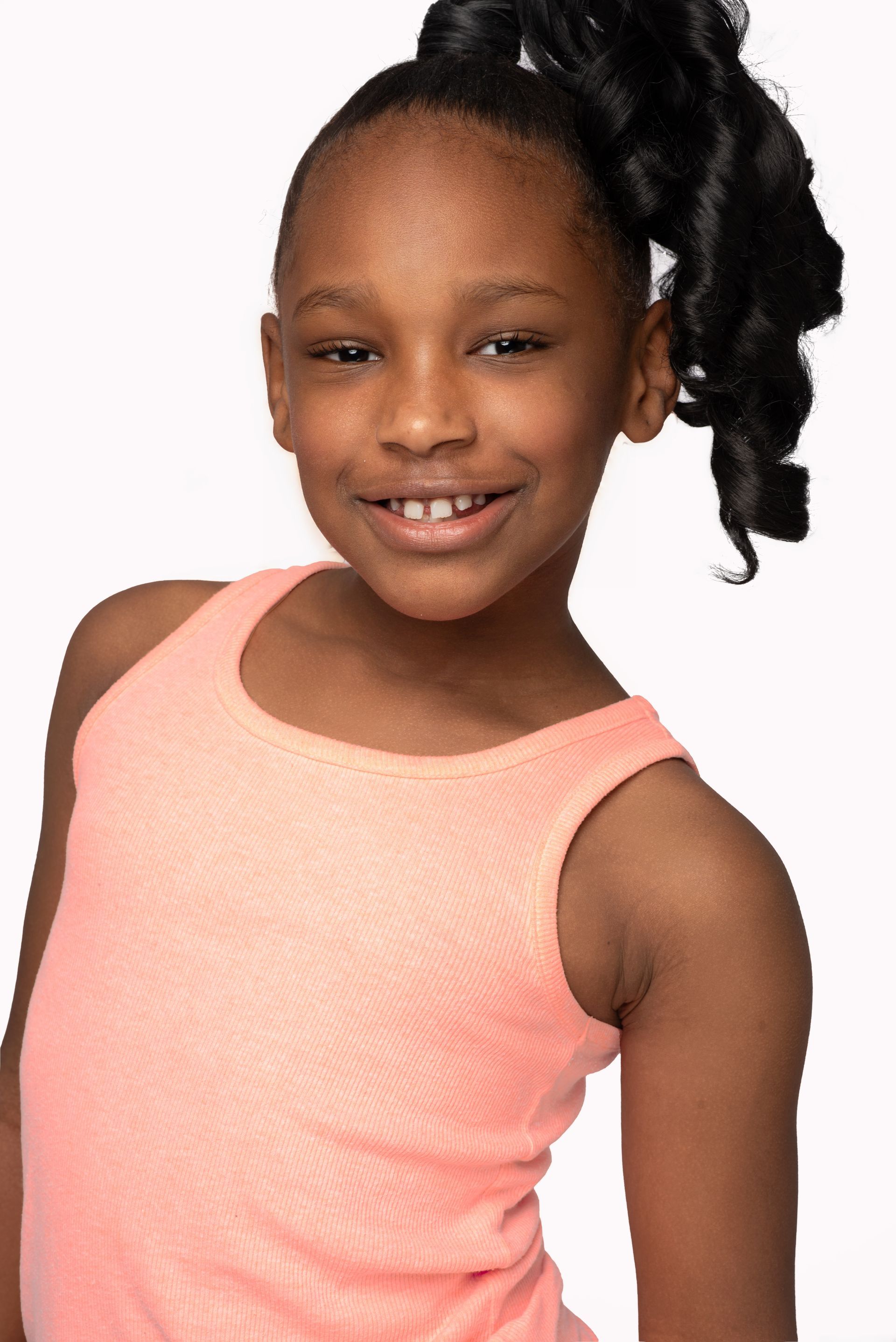 Smiling child in a pink sleeveless top posing against a white background