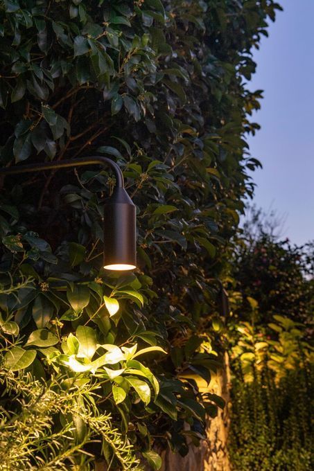 Soggiorno moderno con divano beige, parete nera, lampada da terra e tavolino rotondo.
