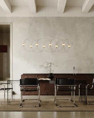 Sala da pranzo moderna con parete in cemento, lampade a sospensione in filo metallico e quattro sedie attorno a un tavolo.