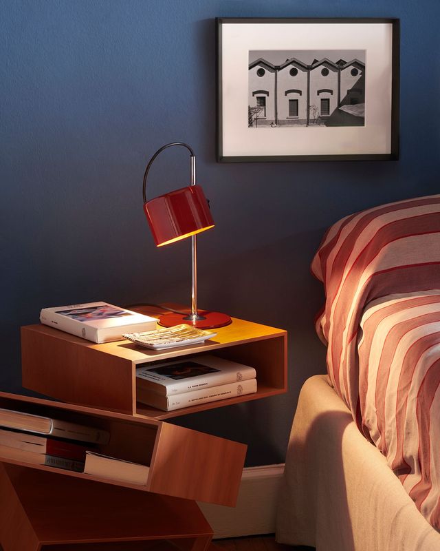 Soggiorno moderno con divano beige, parete nera, lampada da terra e tavolino rotondo.