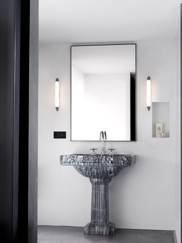 Sala da pranzo minimalista con tavolo bianco, sedia blu, lampada a sospensione dorata e aperture ad arco nelle pareti.