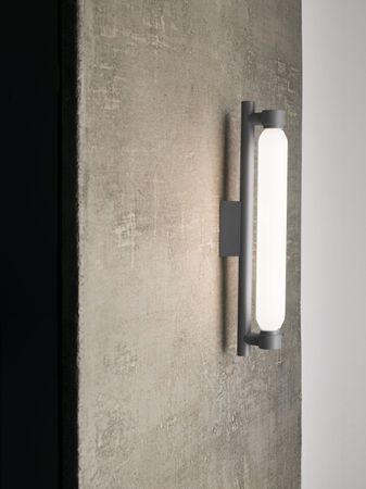 Sala da pranzo moderna con parete in cemento, lampade a sospensione in filo metallico e quattro sedie attorno a un tavolo.