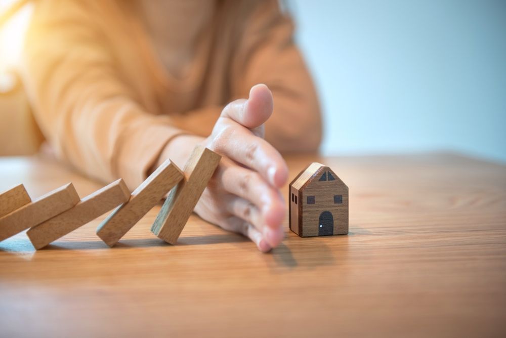A Person is Playing With Wooden Blocks and a Small House on a Wooden Table — Optimus 1 Insurance Brokers in Townsville, QLD