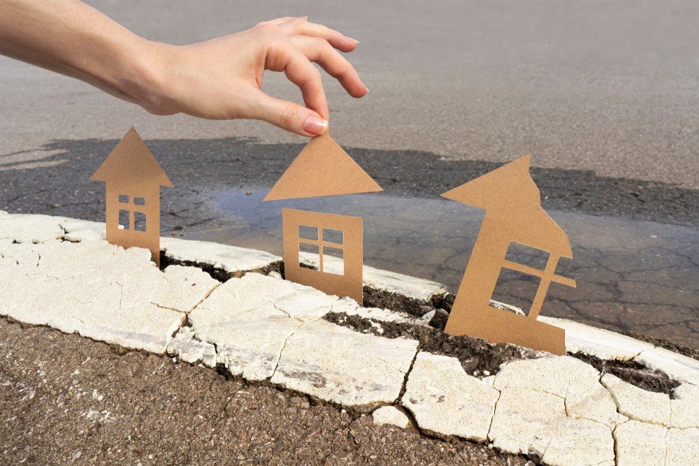 A Person is Holding a Cardboard House With an Arrow Pointing Up — Optimus 1 Insurance Brokers in Brisbane, QLD
