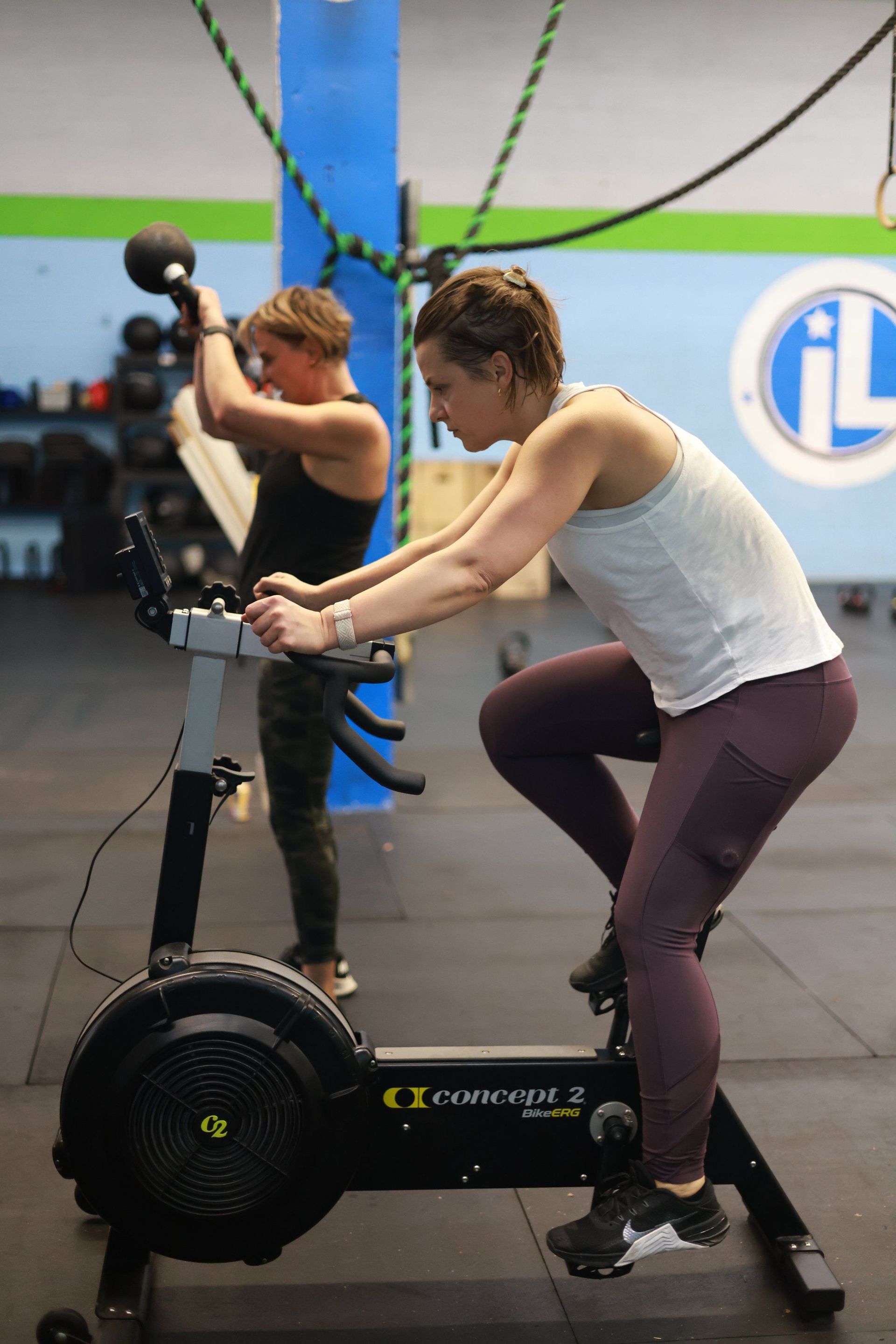 Two women are riding exercise bikes in a gym.