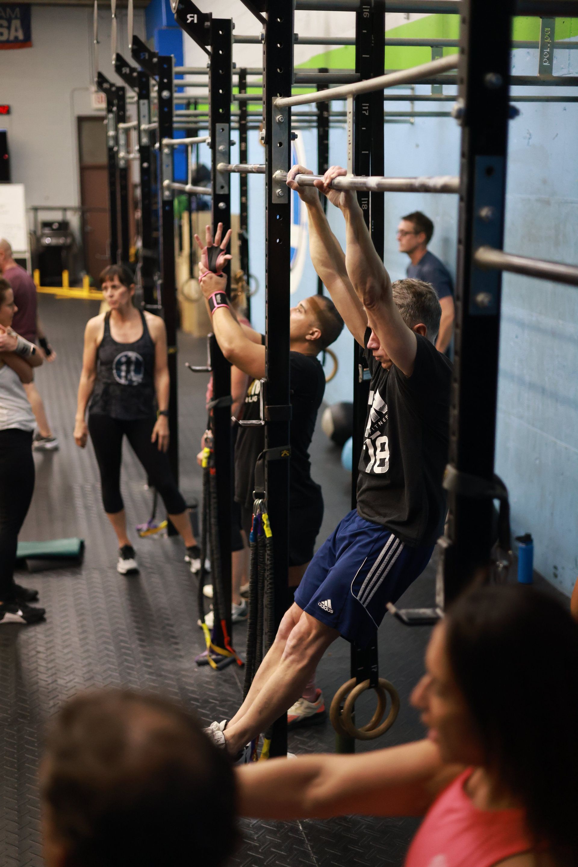 A group of people are doing pull ups in a gym.
