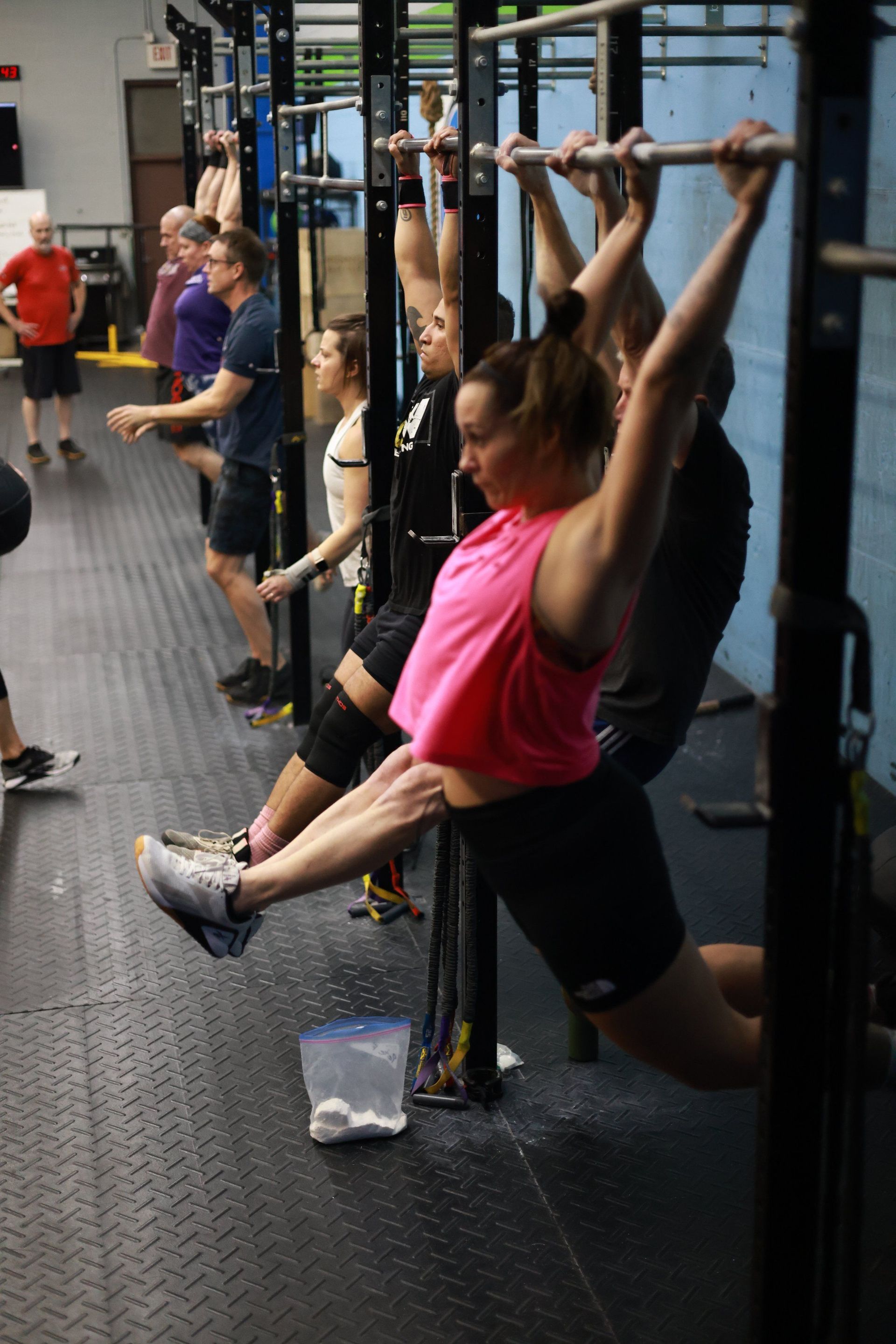 A group of people are doing pull ups in a gym.