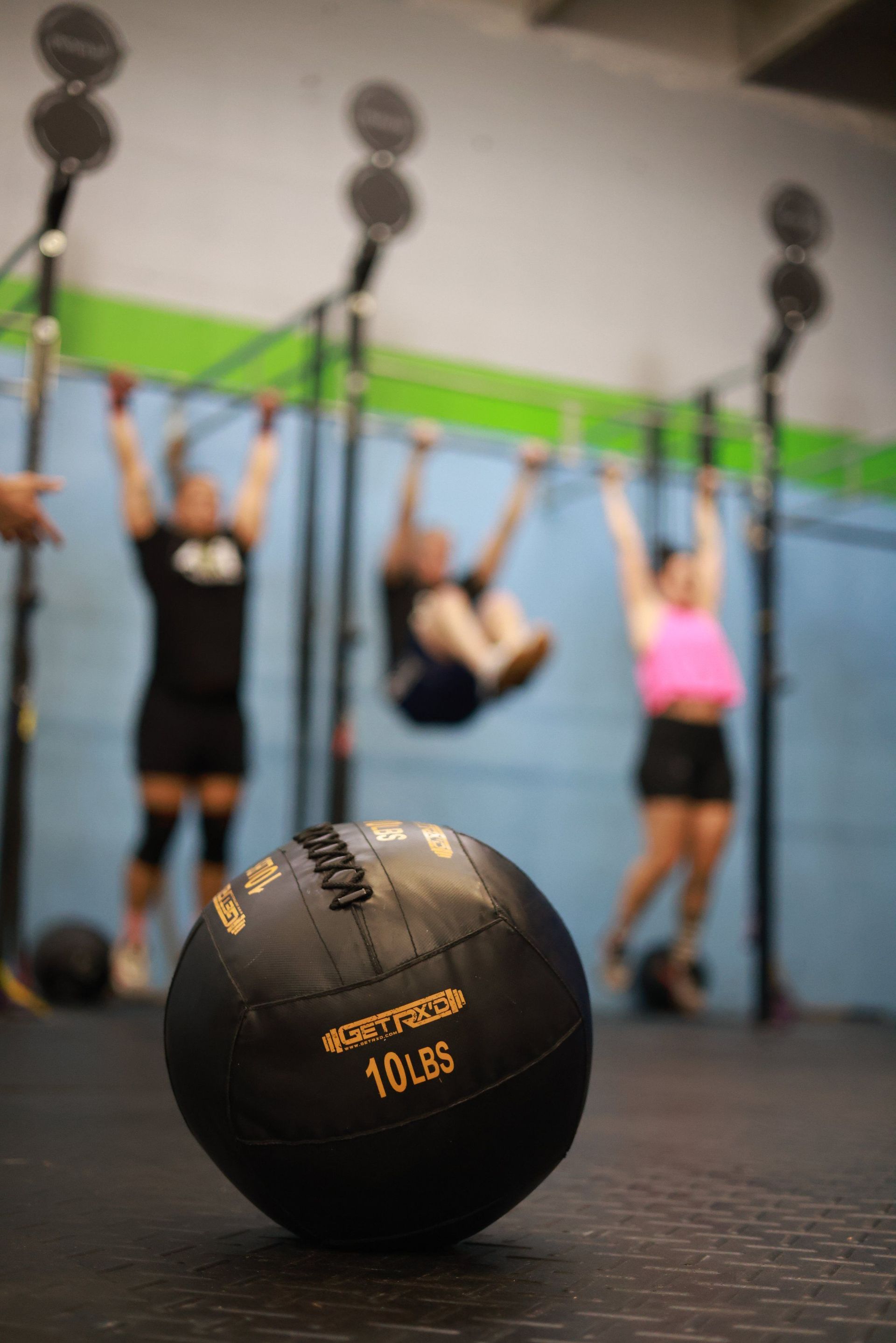 A group of people are doing exercises in a gym with a ball in the foreground.