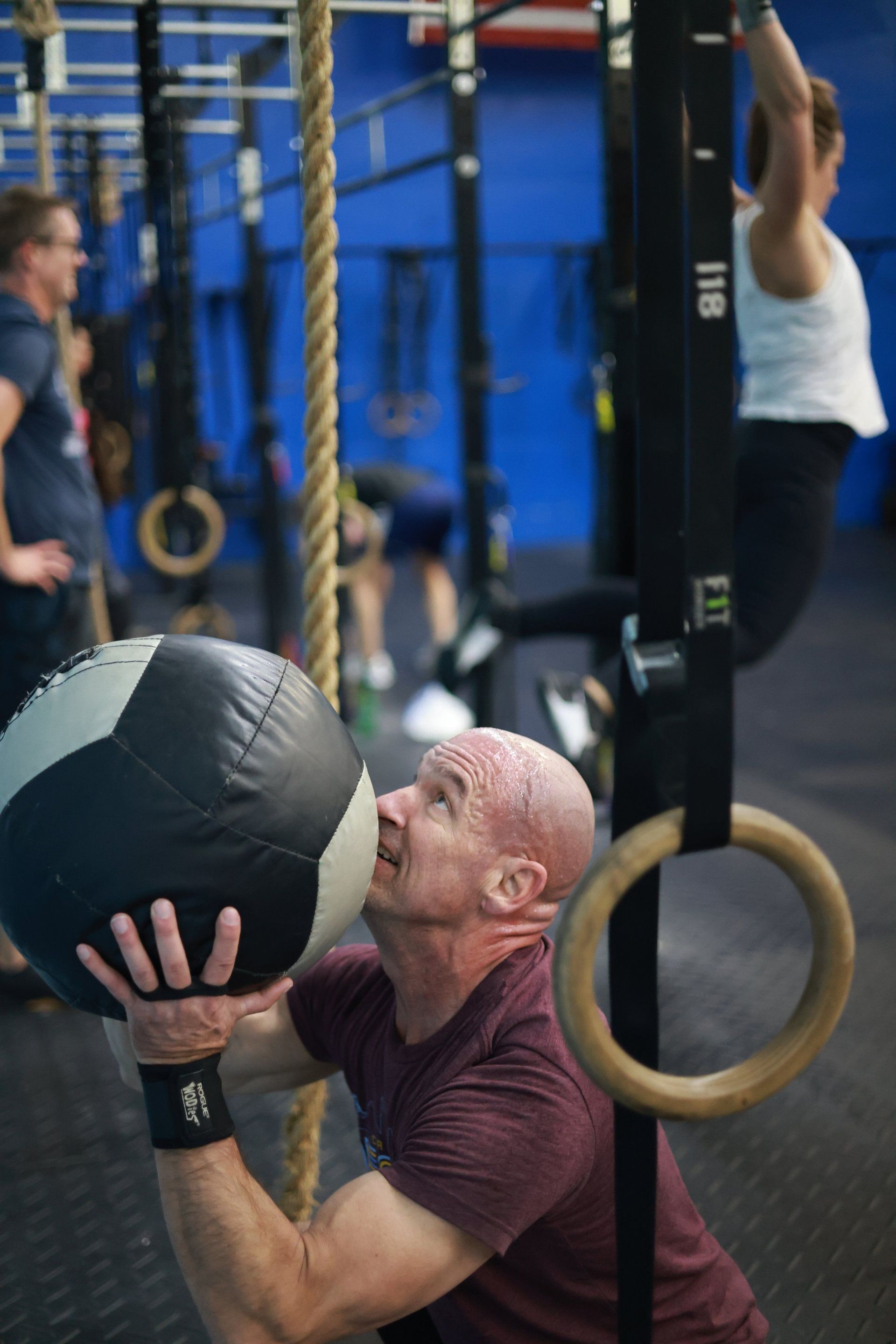A man is holding a medicine ball over his head in a gym.