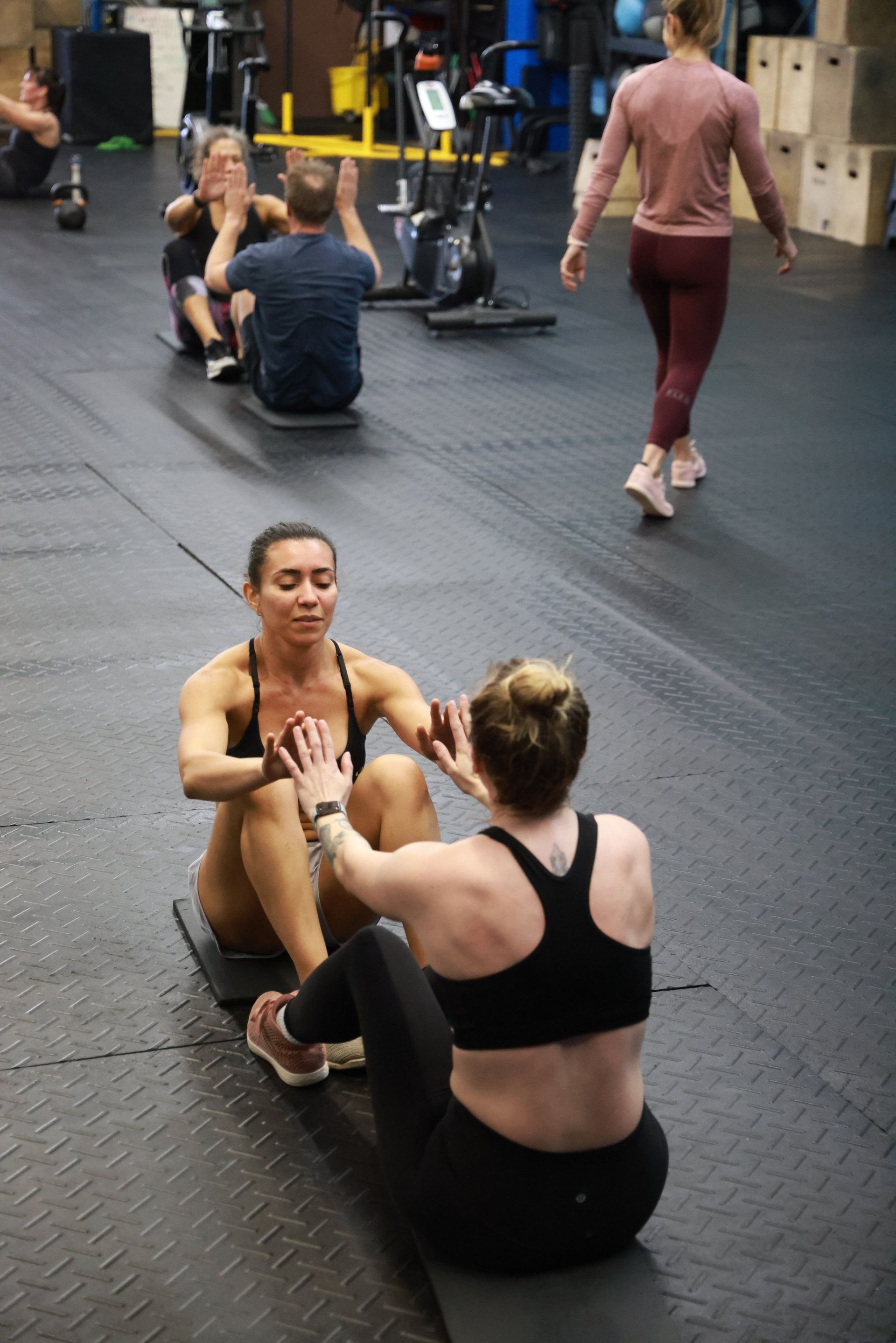 A group of people are doing sit ups in a gym.