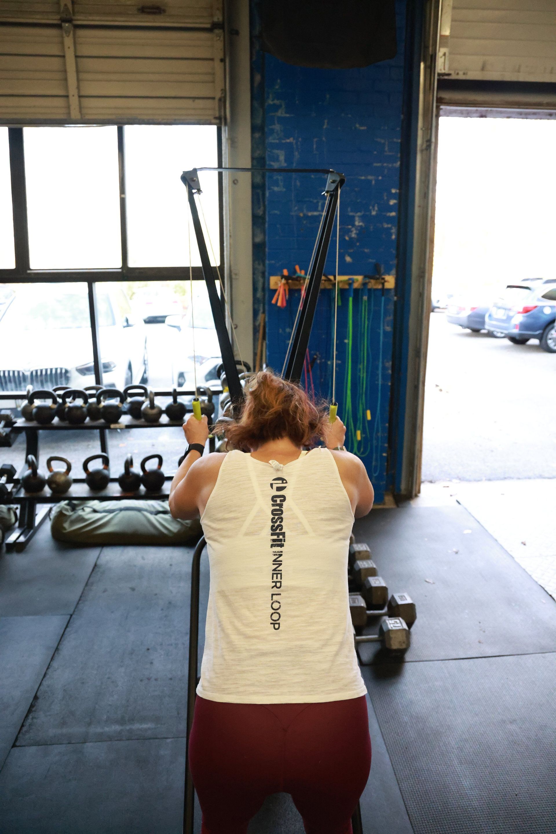 A woman is kneeling down in a gym holding a barbell.