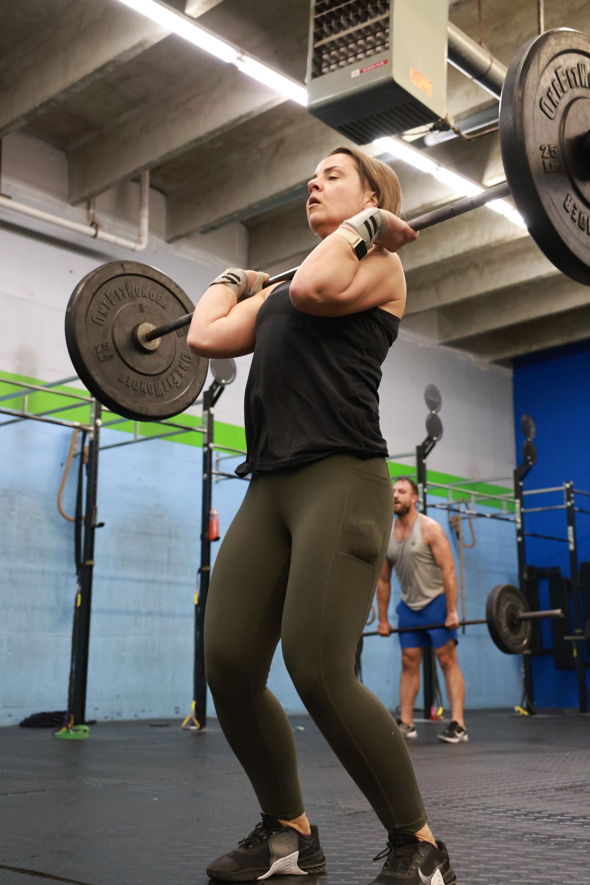 A woman is lifting a barbell in a gym.