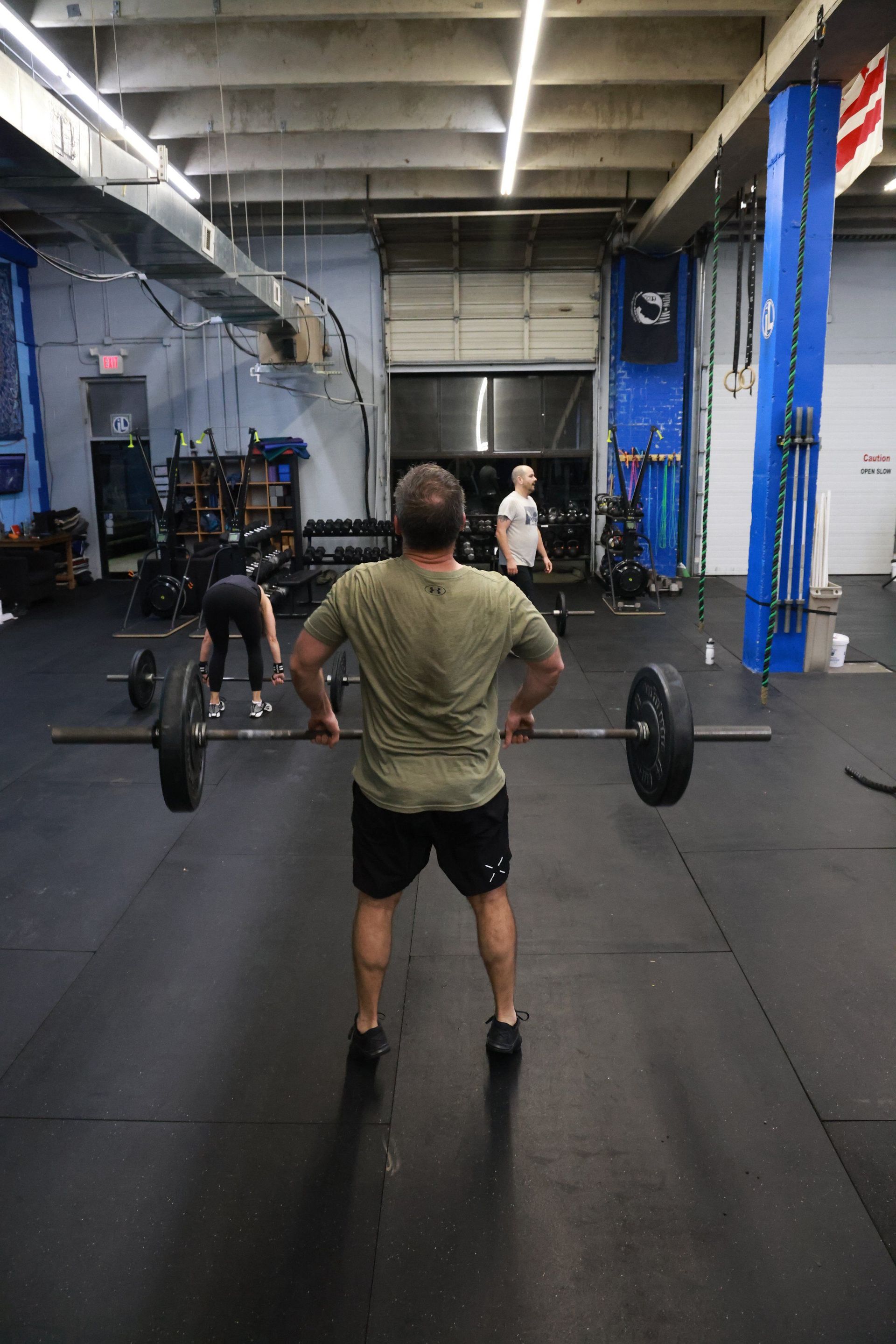 A man is lifting a barbell in a gym.