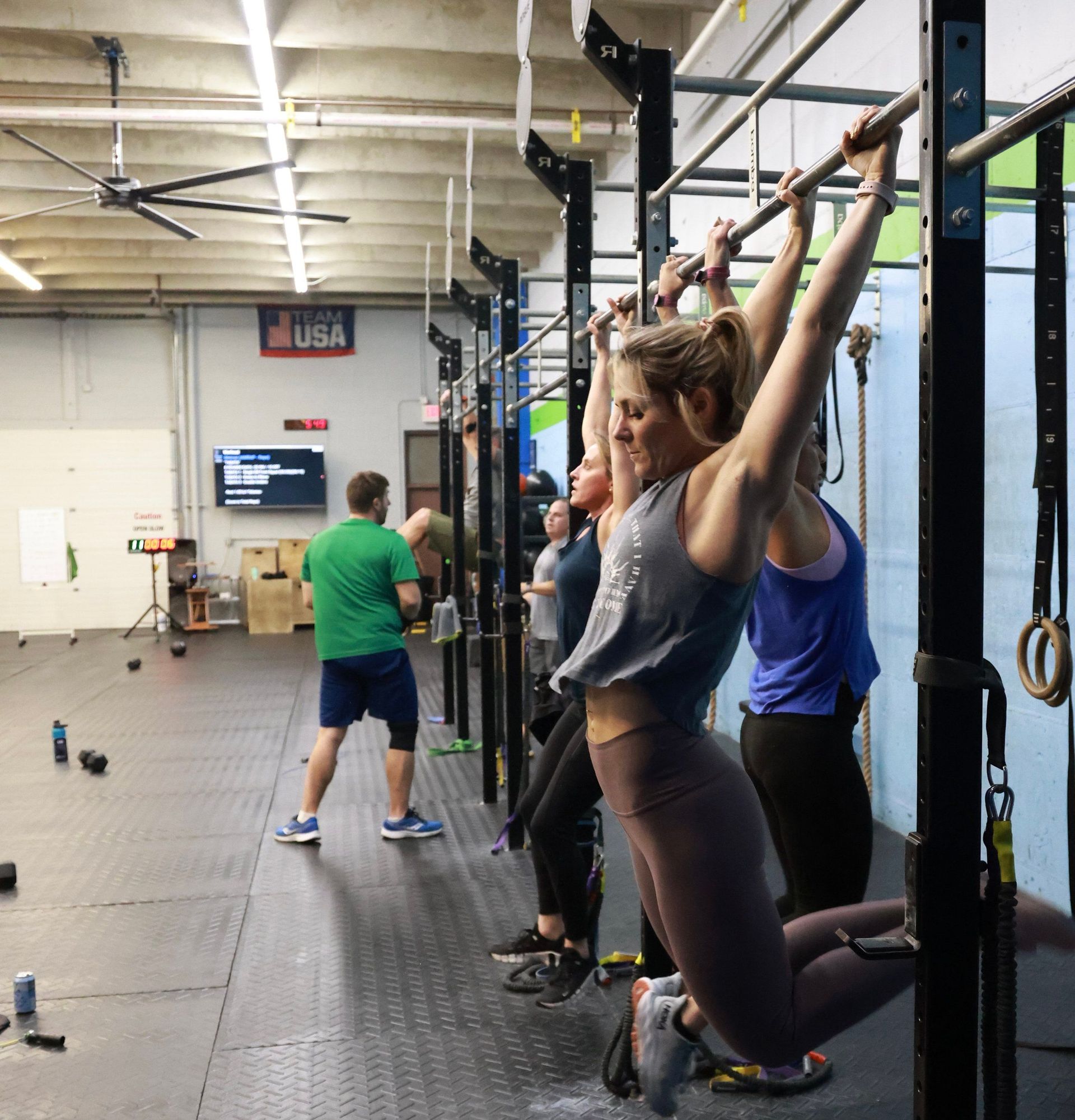 A group of people are doing pull ups in a gym