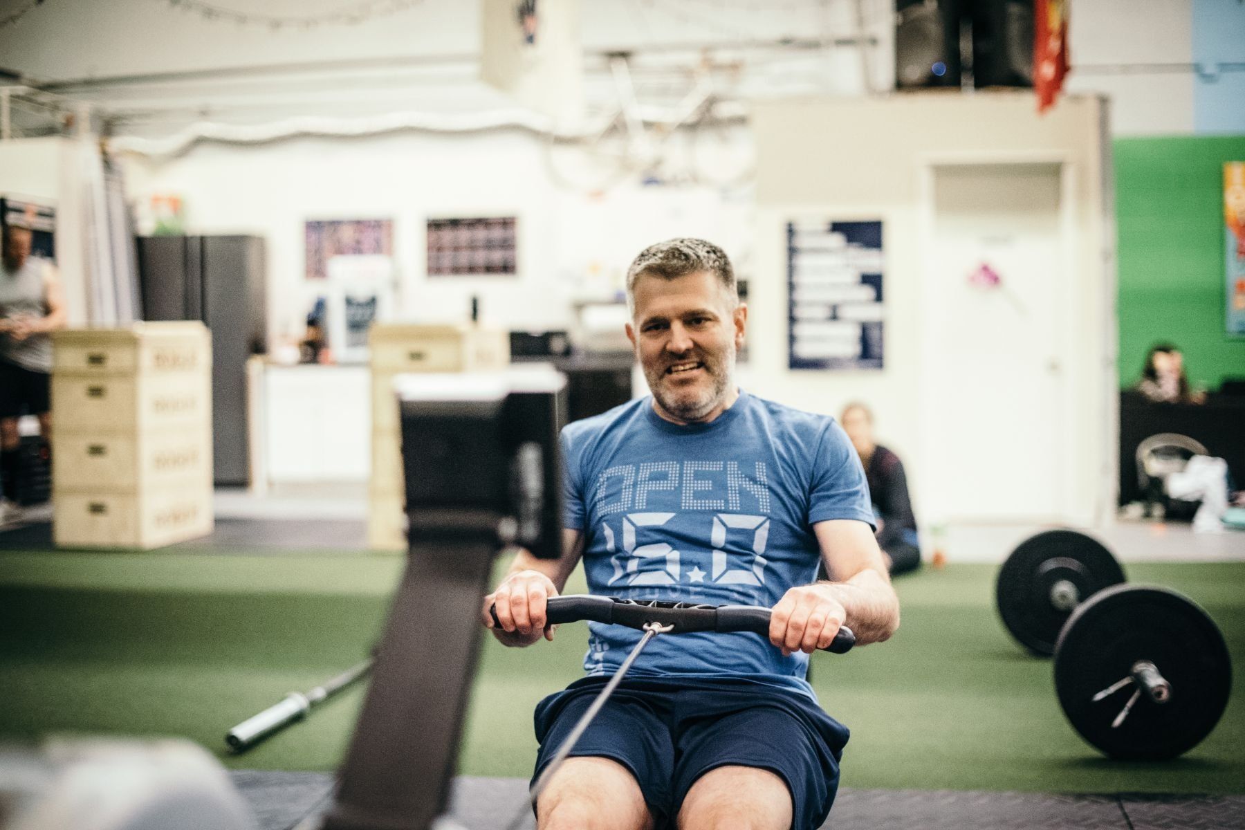 A man is rowing a rowing machine in a gym.