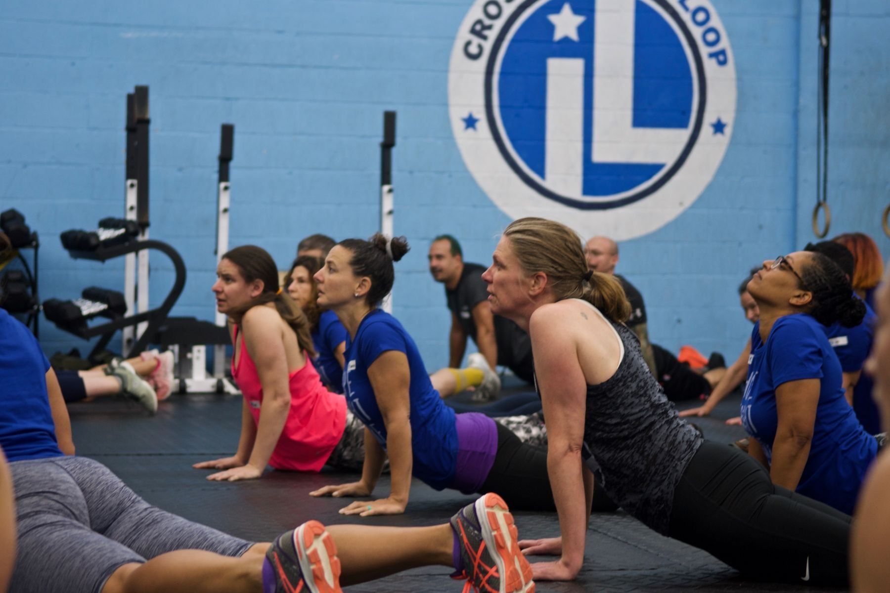 A group of people are doing push ups in front of a sign that says cross loop
