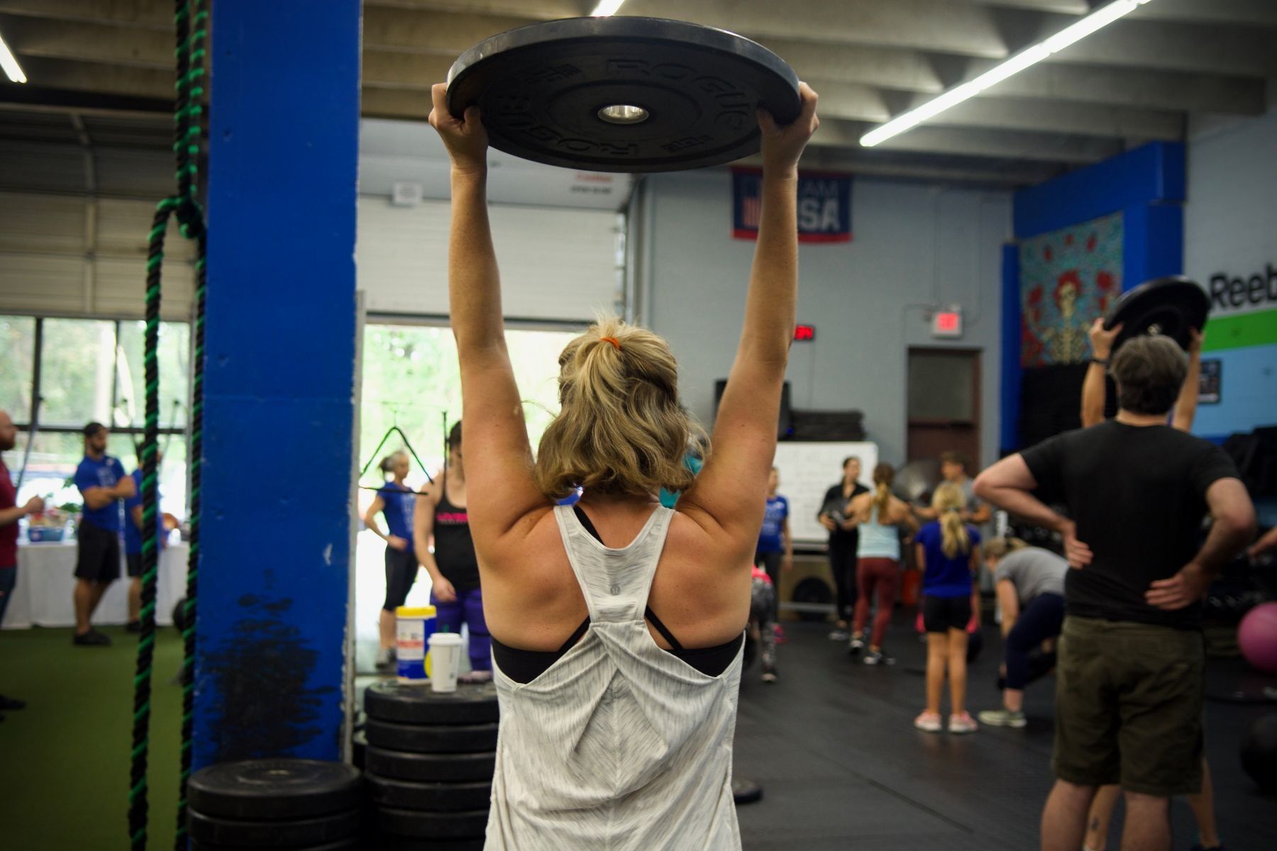 A woman is lifting a weight over her head in a gym.