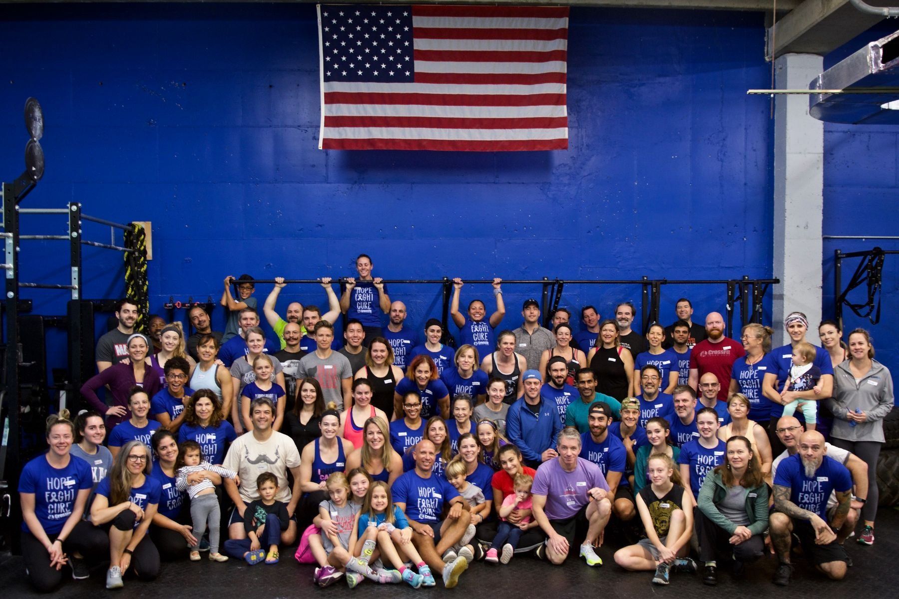 A large group of people are posing for a picture in front of an american flag.