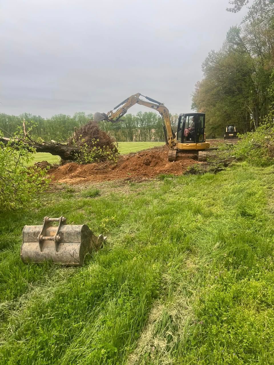 A bulldozer is moving dirt in a grassy field.