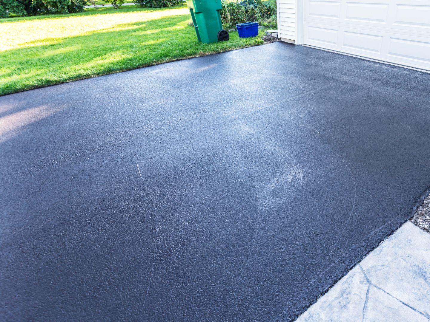 Freshly seal coated asphalt driveway in Maryland completed by CM Ayres, featuring a smooth, dark finish and clean edges