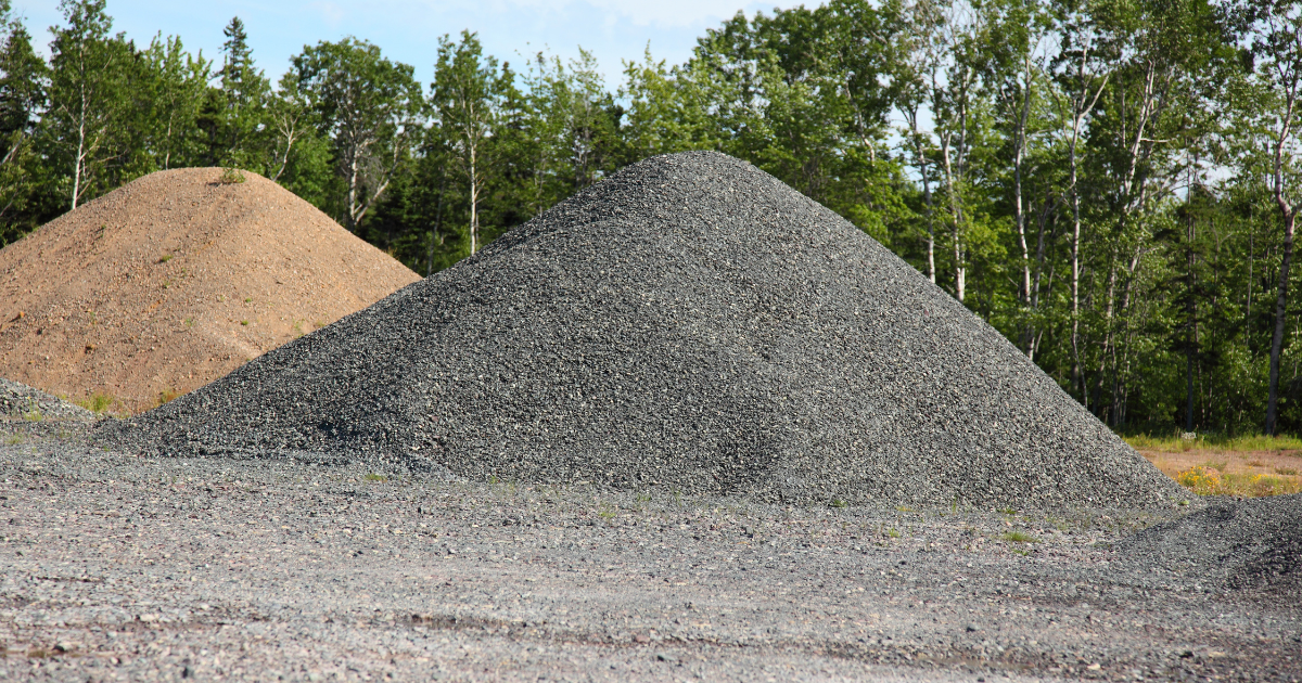 Two piles of gravel are stacked on top of each other in a field.