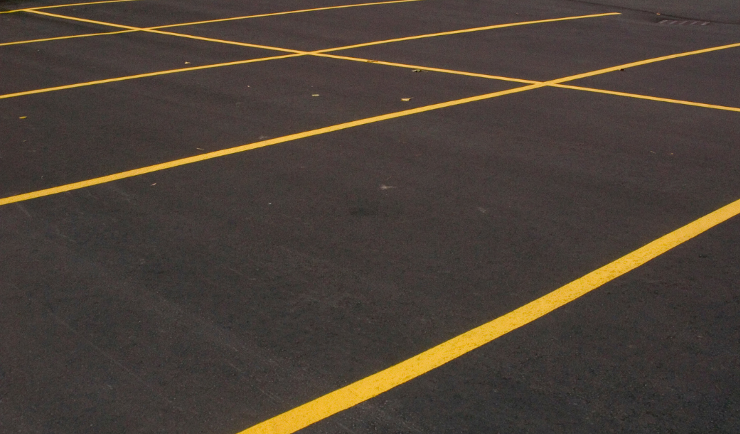 Empty parking lot with yellow painted lines on dark pavement