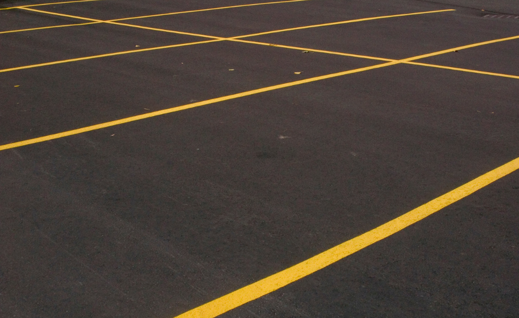 Empty parking lot with diagonal yellow lane lines on dark pavement