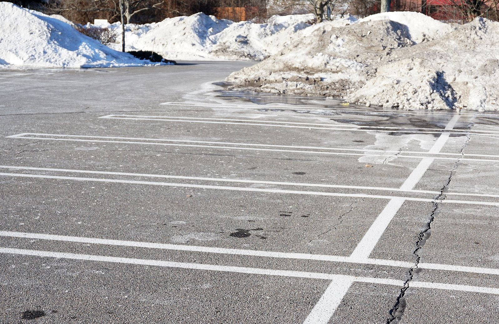Empty snow-covered parking lot with white painted lines and snowbanks in the background