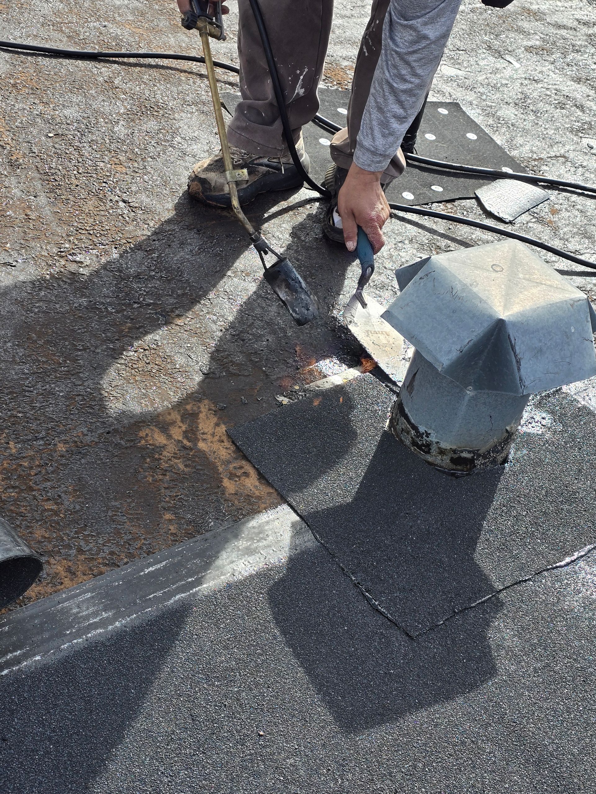 Worker repairing a roof vent on a shingled rooftop