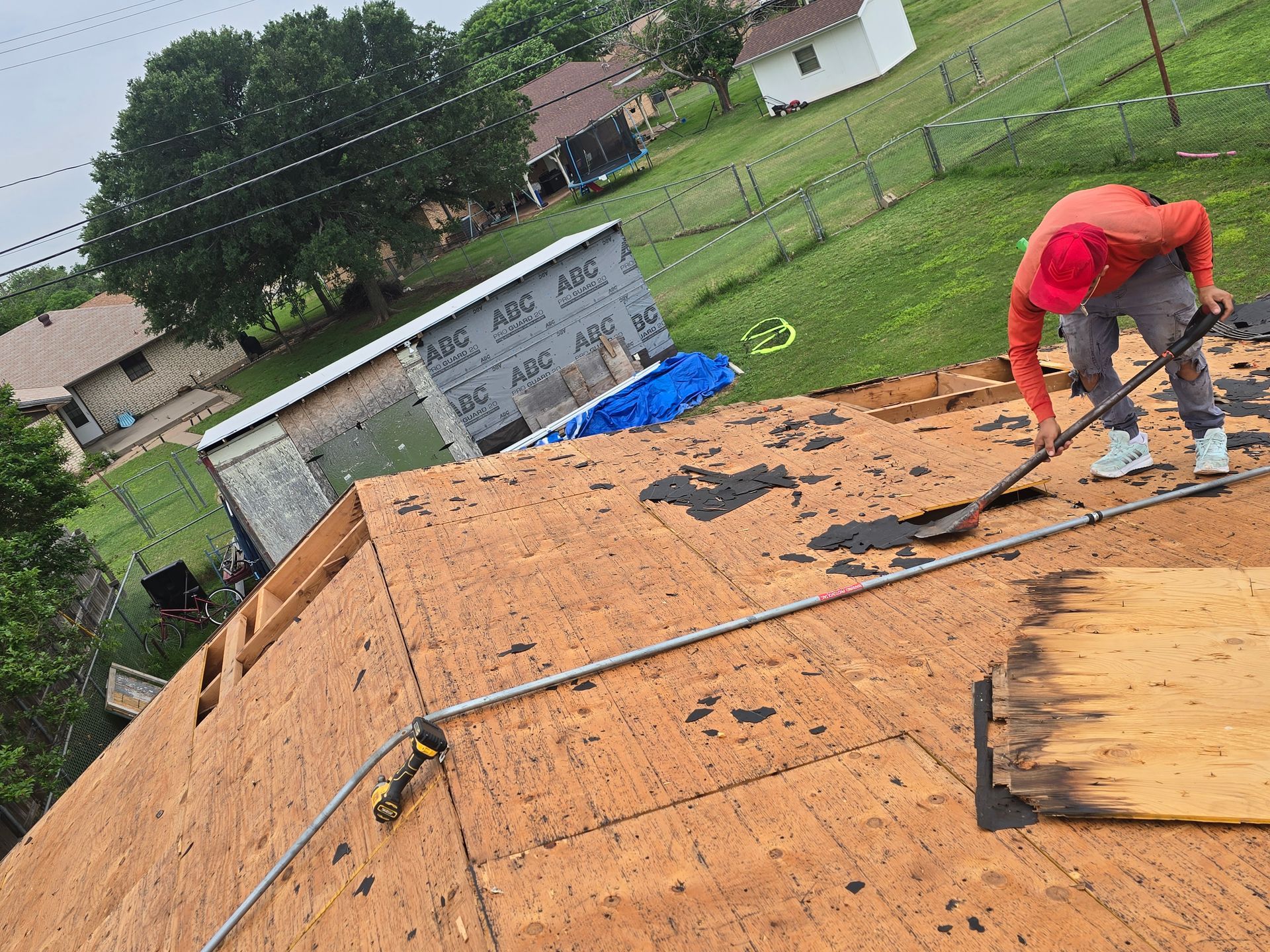 Worker installing roofing on a plywood roof under construction outdoors