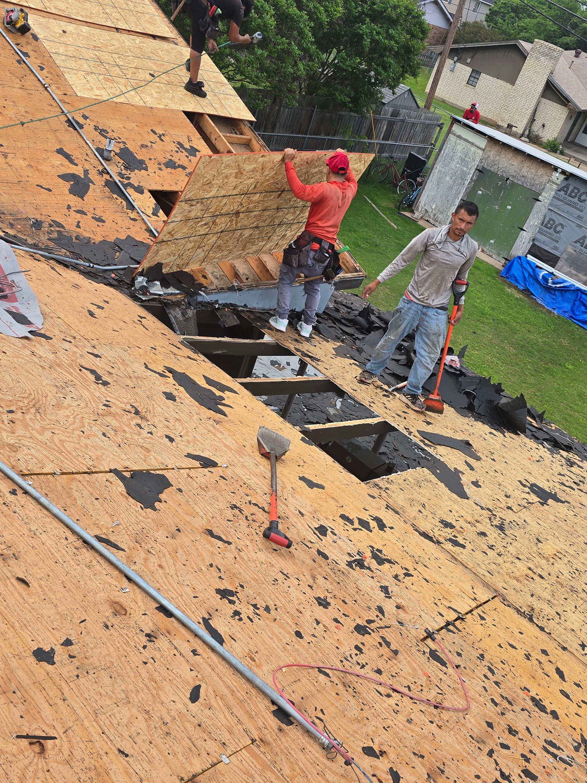 Workers carrying straw on a sloped roof during repair work