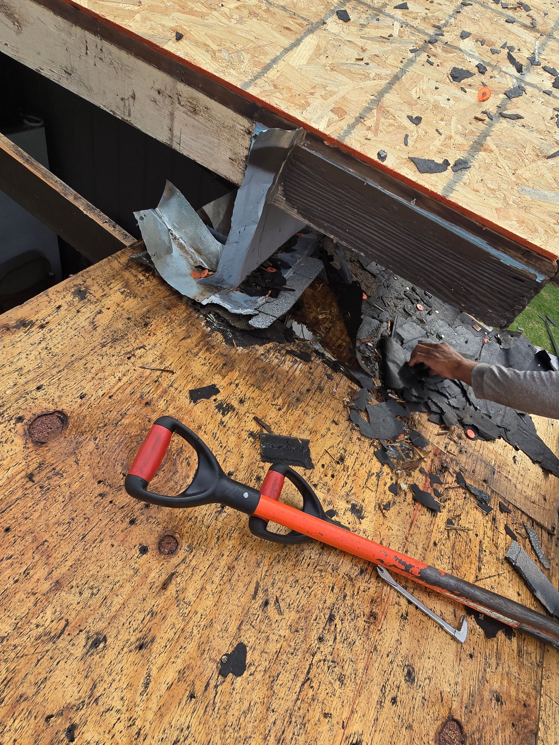 Rusty metal surface with a broken joint and a red-handled pipe wrench lying nearby.