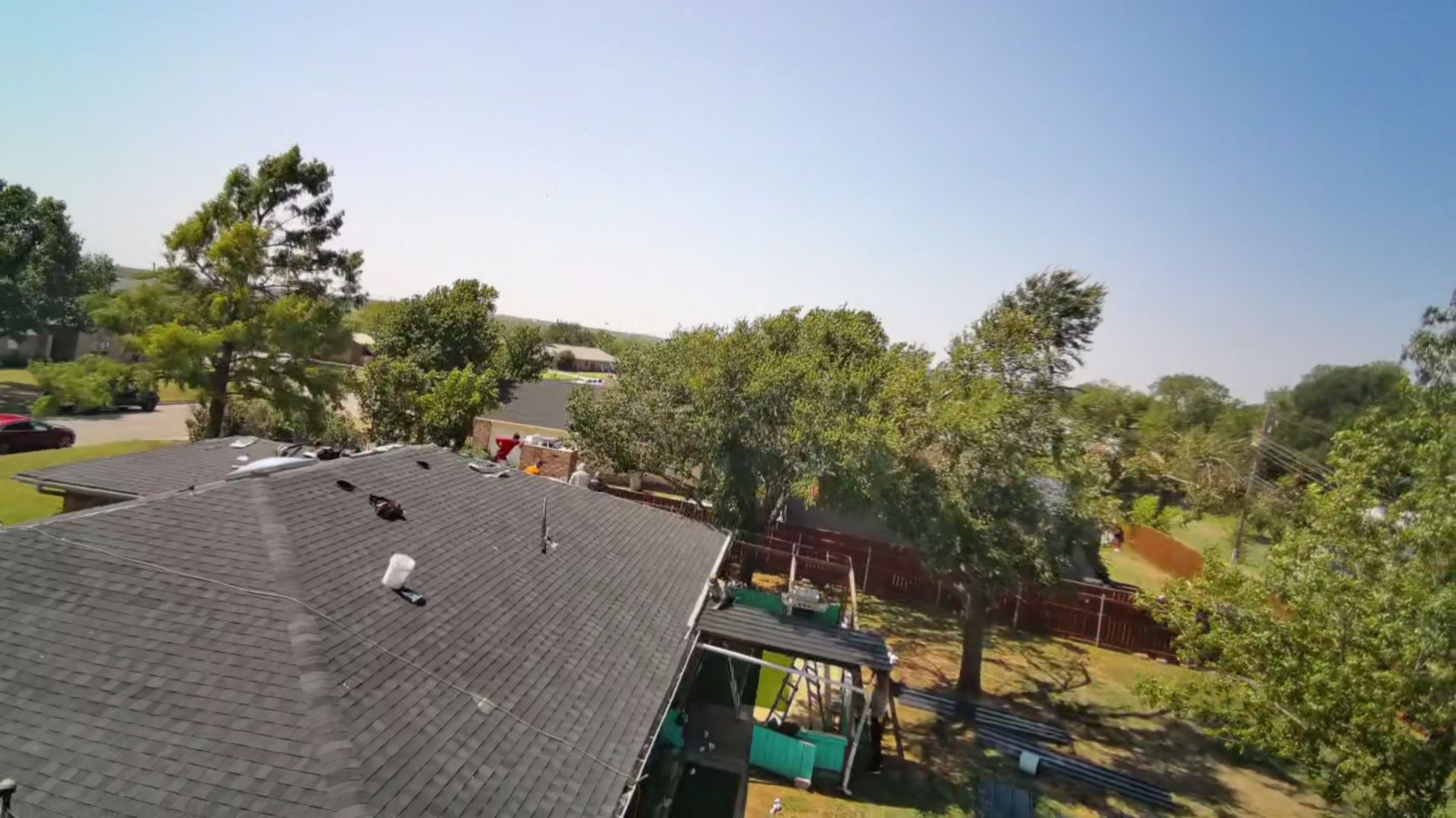 Suburban neighborhood with rooftops, trees, and a clear blue sky on a sunny day