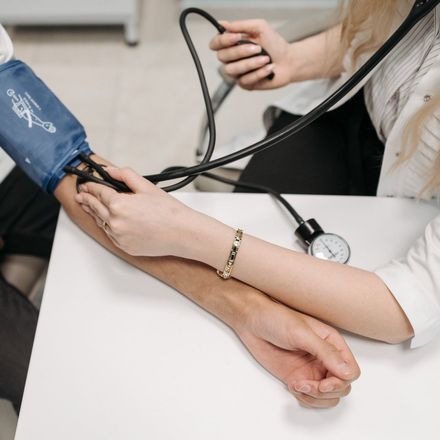 Person having blood pressure taken by medical professional; setting is a doctor's office.