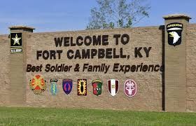 Welcome to Fort Campbell, KY sign with military insignias on a brick wall