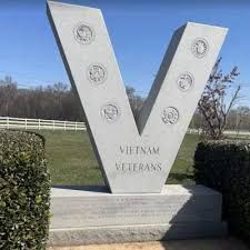 Vietnam Veterans memorial monument with a large white V in a grassy outdoor setting