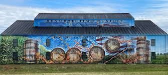 Large blue-roofed building with a colorful mural of barrels and industrial tanks on the side