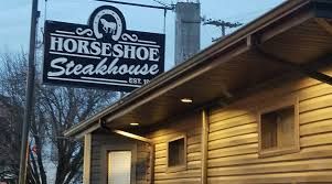 Horseshoe Steakhouse sign above a wooden building at dusk
