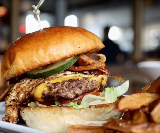 Close-up of a cheeseburger with lettuce, bacon, and a toasted bun on a table
