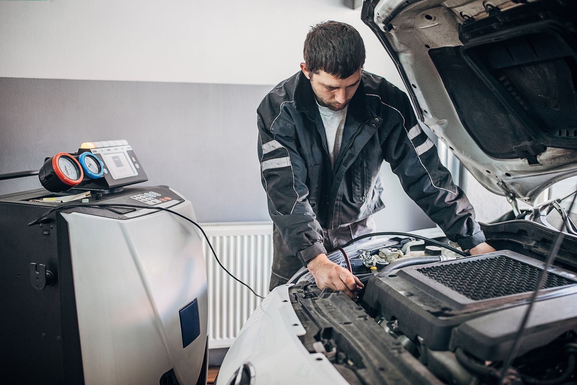 A man is working on the engine of a car with the hood open.