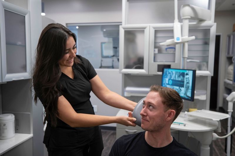 A woman is examining a man 's teeth in a dental office.